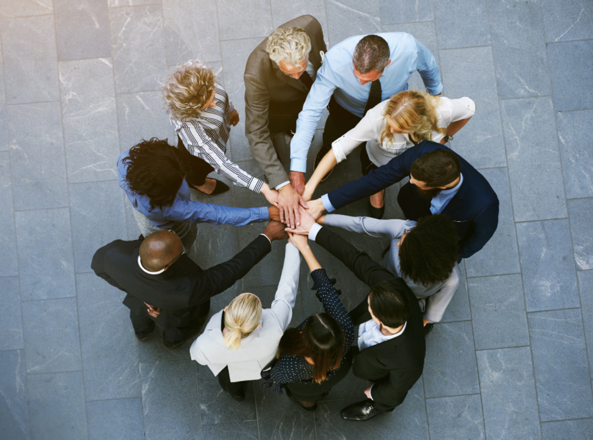 team standing in circle with hands in the middle